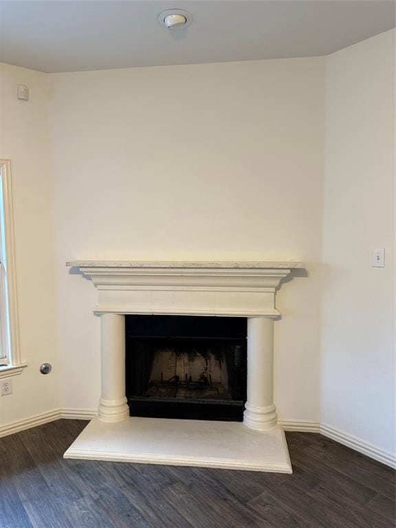 interior details with baseboards, a fireplace with raised hearth, and wood finished floors