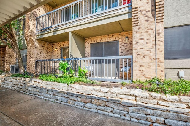 8888 Tallwood Dr Unit 1110, Austin, TX 78759 - view of exterior entry featuring covered porch, central AC unit, brick siding, and a balcony