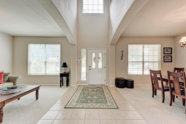tiled foyer entrance featuring carpet floors, a notable chandelier, and a wealth of natural light