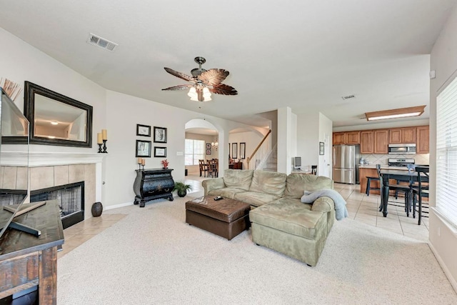 living room featuring arched walkways, light colored carpet, visible vents, and a fireplace