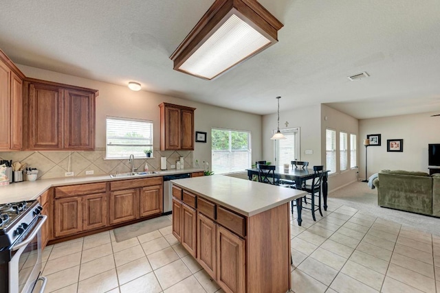 kitchen with appliances with stainless steel finishes, a sink, light tile patterned floors, light countertops, and open floor plan