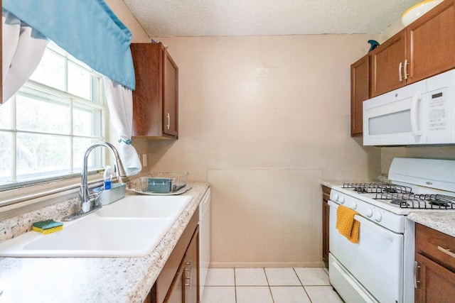 kitchen featuring brown cabinetry, white appliances, light countertops, a textured ceiling, and a sink