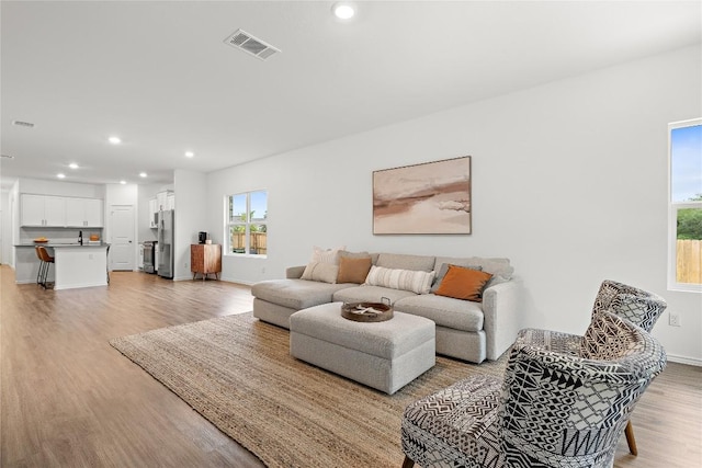 living area featuring visible vents, recessed lighting, light wood-style floors, and baseboards