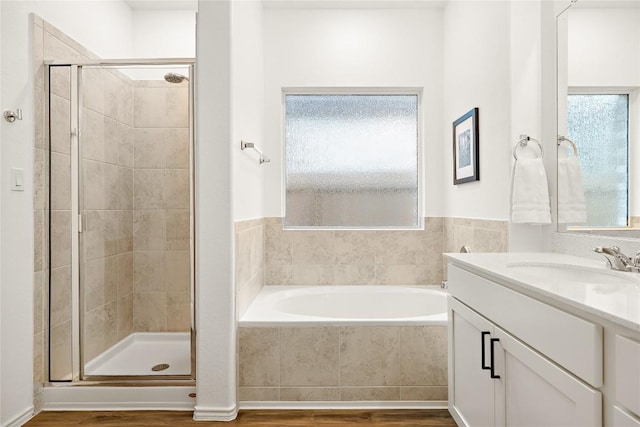 full bathroom featuring vanity, wood finished floors, a garden tub, and a stall shower