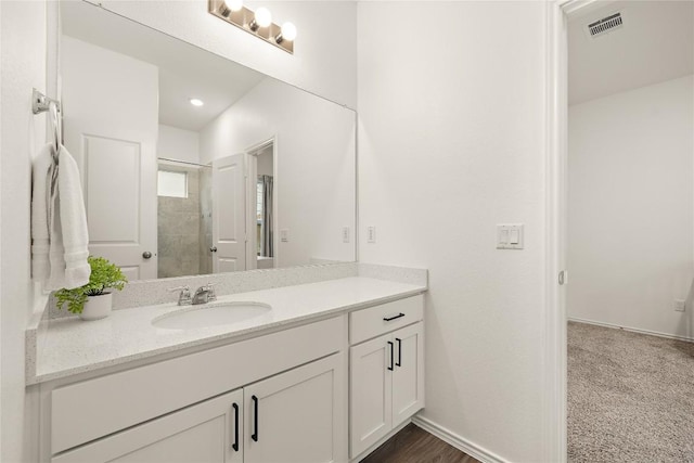 bathroom featuring vanity, baseboards, a shower stall, and visible vents