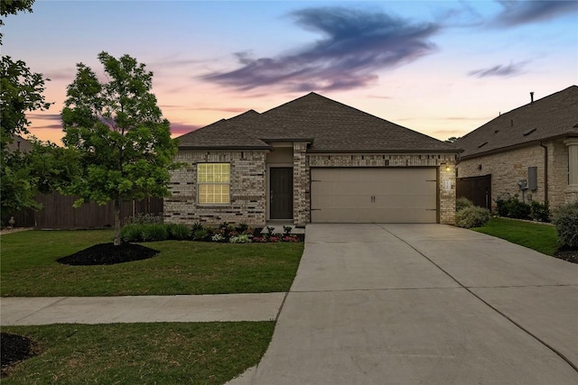 view of front facade featuring a front yard, a garage, brick siding, fence, and concrete driveway