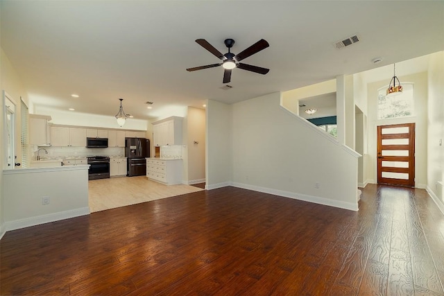 unfurnished living room featuring ceiling fan, a sink, baseboards, light wood-type flooring, and visible vents