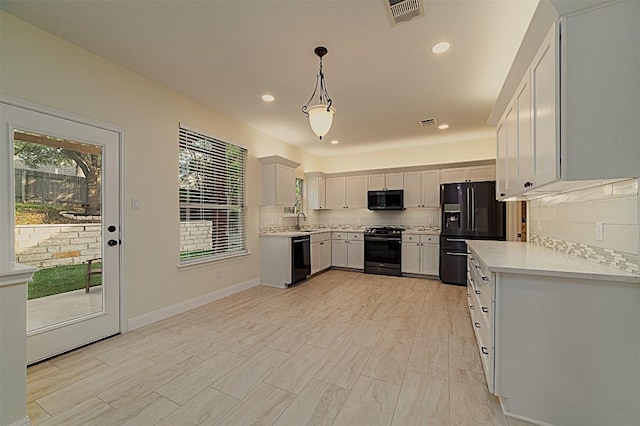 kitchen featuring plenty of natural light, light countertops, backsplash, and black appliances