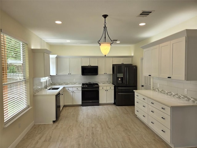 kitchen featuring a sink, backsplash, black appliances, and light countertops