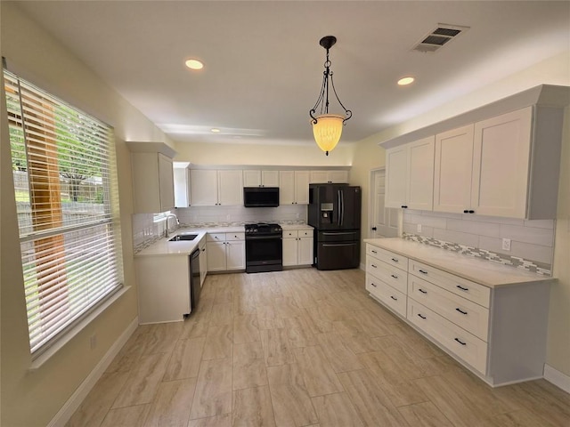 kitchen with visible vents, decorative backsplash, light countertops, a sink, and black appliances