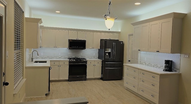 kitchen featuring light countertops, a sink, black appliances, and tasteful backsplash