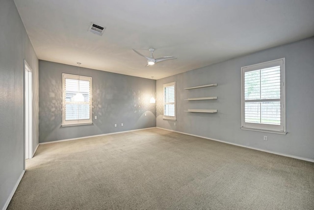 carpeted spare room with a healthy amount of sunlight, baseboards, and visible vents