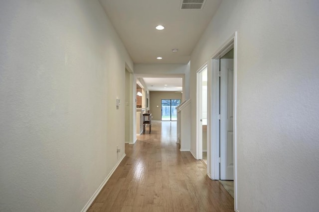 hallway with recessed lighting, baseboards, visible vents, and light wood finished floors