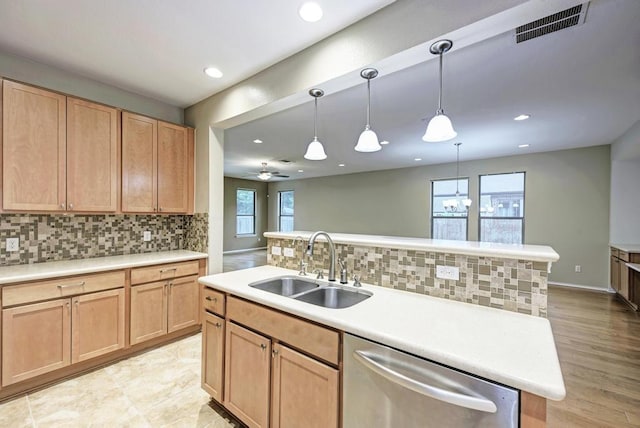 kitchen featuring a sink, dishwasher, backsplash, visible vents, and a center island with sink
