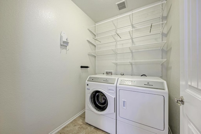 clothes washing area with baseboards, laundry area, washing machine and dryer, and visible vents