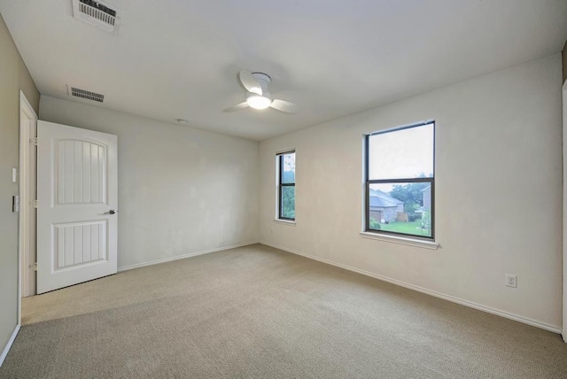 carpeted empty room with visible vents, baseboards, and ceiling fan