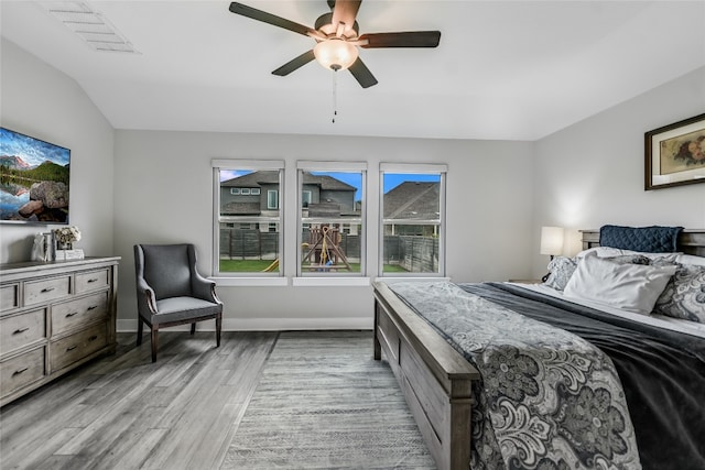 bedroom with ceiling fan, visible vents, vaulted ceiling, baseboards, and light wood-style flooring
