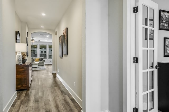 corridor with arched walkways, baseboards, dark wood finished floors, and recessed lighting