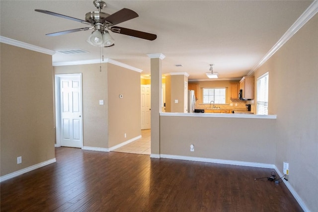 unfurnished living room with a sink, ornamental molding, ceiling fan, and visible vents
