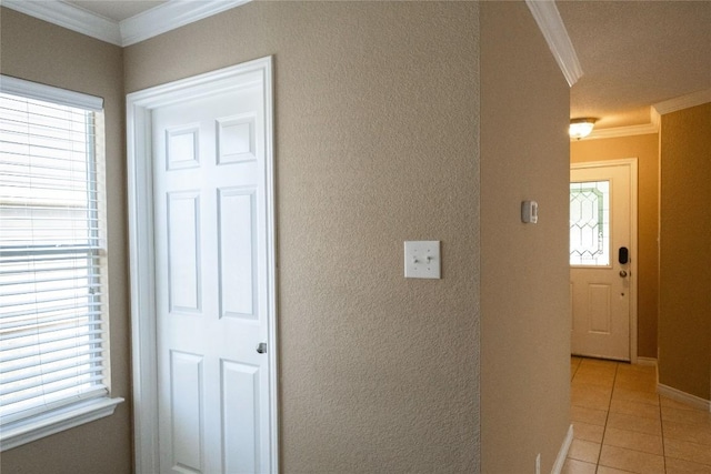 hallway featuring crown molding, baseboards, a textured wall, and light tile patterned floors