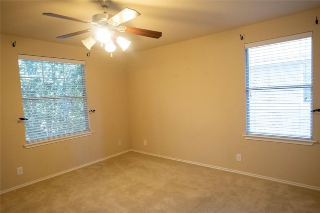 empty room with a ceiling fan, baseboards, light carpet, and a healthy amount of sunlight