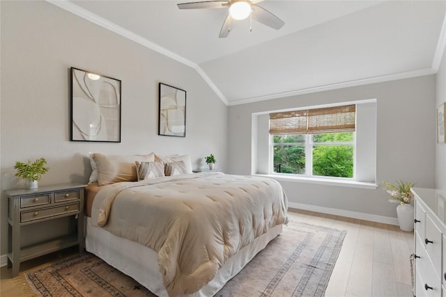 bedroom with crown molding, ceiling fan, light wood-style floors, baseboards, and vaulted ceiling