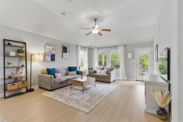living area featuring baseboards, a ceiling fan, and light wood finished floors