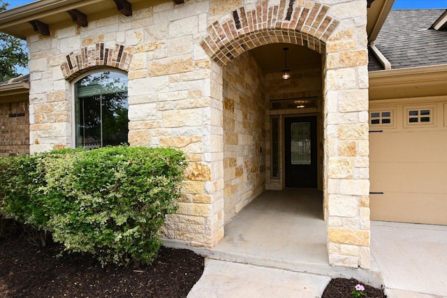 view of exterior entry featuring a shingled roof and stone siding