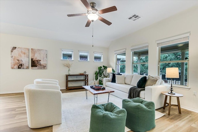 living room featuring light wood-style floors, baseboards, a ceiling fan, and visible vents