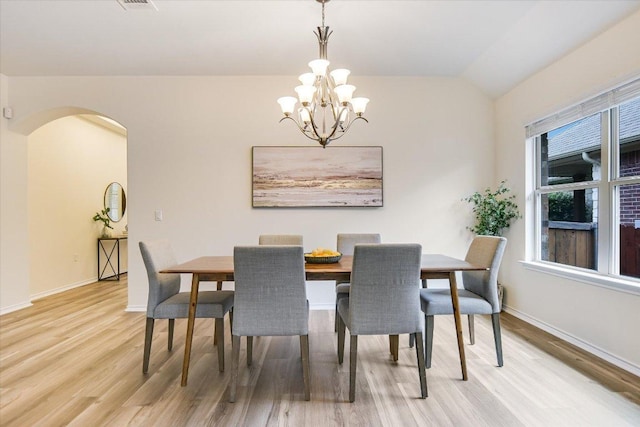 dining area with an inviting chandelier, baseboards, arched walkways, and wood finished floors