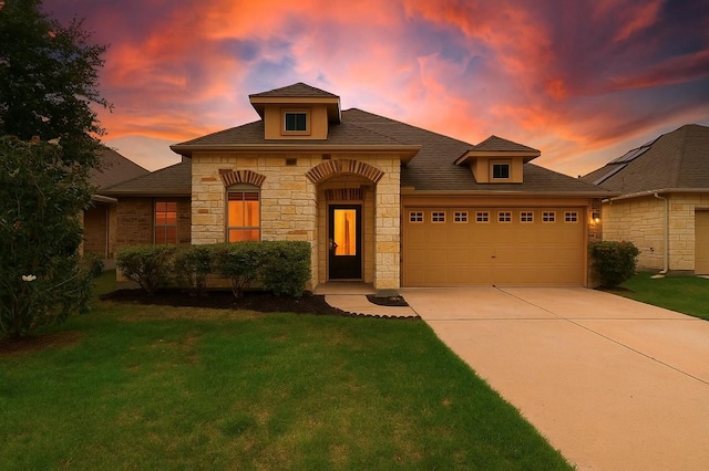 view of front of home featuring a lawn, concrete driveway, and stone siding