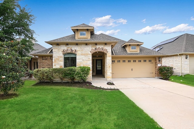 french country style house with concrete driveway, an attached garage, stone siding, and a front lawn