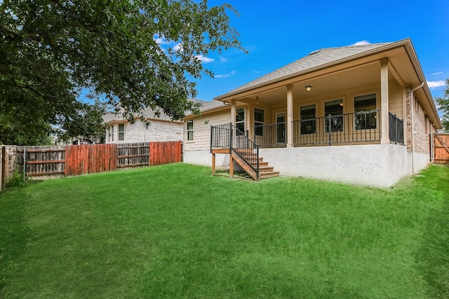 rear view of house featuring a lawn and a fenced backyard
