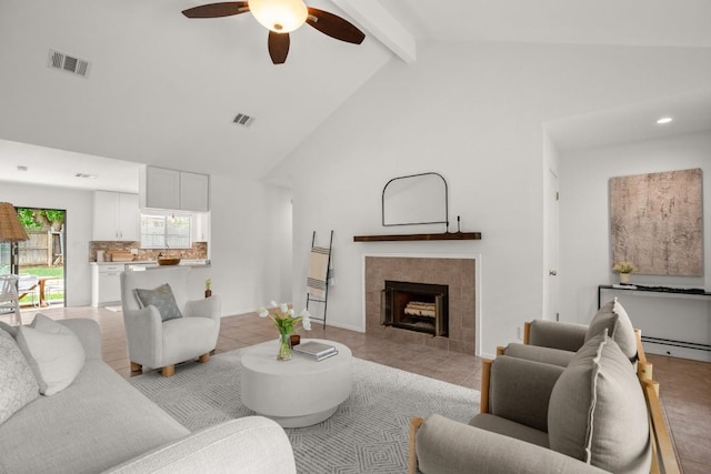 living area with visible vents, beamed ceiling, high vaulted ceiling, a tiled fireplace, and a ceiling fan