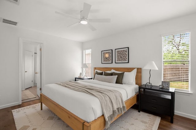 bedroom featuring a ceiling fan, baseboards, visible vents, and wood finished floors