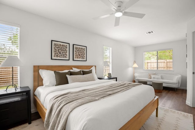 bedroom featuring a ceiling fan, visible vents, and wood finished floors