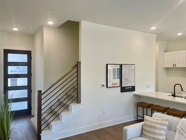 interior space featuring baseboards, a kitchen breakfast bar, dark wood-style floors, white cabinets, and a sink