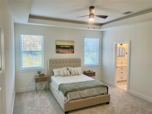 bedroom featuring visible vents, a raised ceiling, light carpet, and multiple windows