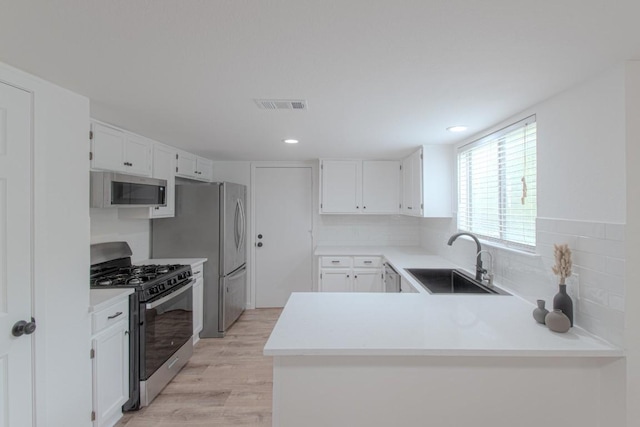 kitchen with visible vents, light wood-style flooring, a sink, stainless steel appliances, and white cabinetry