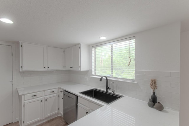kitchen with decorative backsplash, dishwasher, a sink, light countertops, and white cabinetry