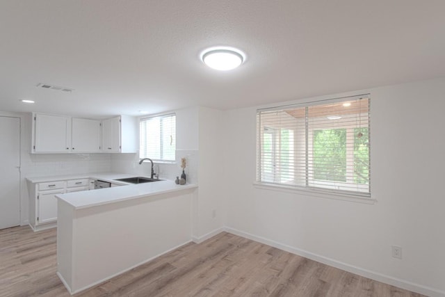 kitchen with white cabinetry, visible vents, a sink, and light wood-style floors