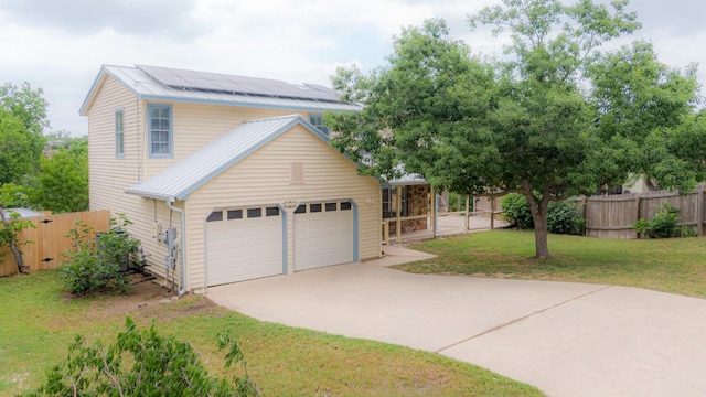 view of front of house with fence, an attached garage, a front lawn, roof mounted solar panels, and concrete driveway