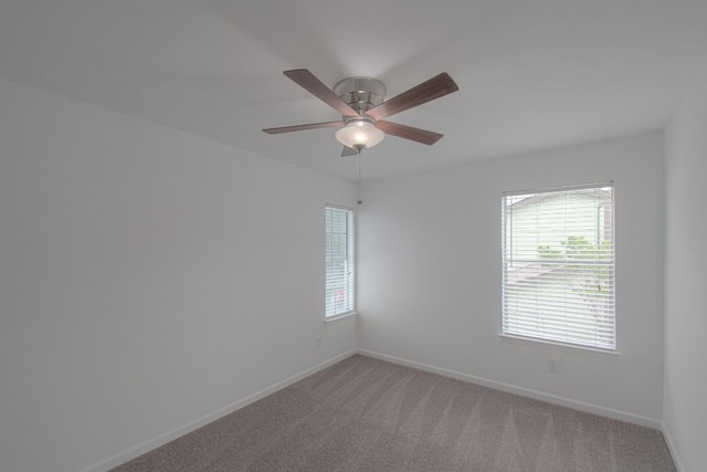 empty room with a ceiling fan, baseboards, and light carpet