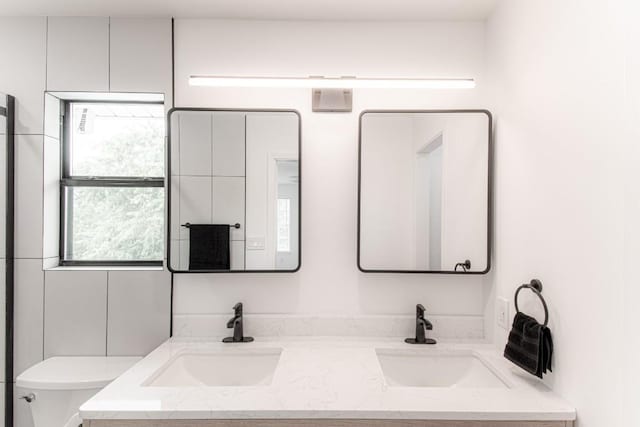 full bathroom featuring a sink, toilet, and double vanity