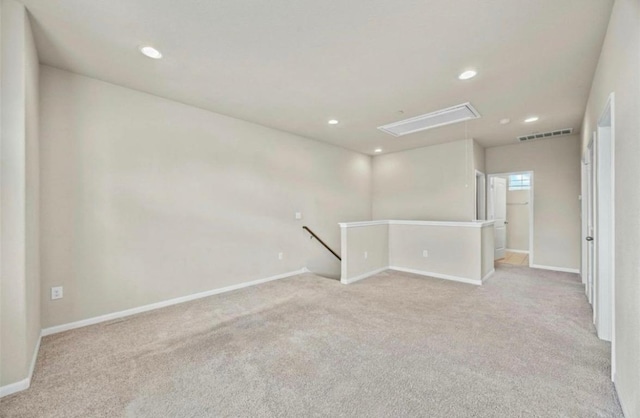 spare room with visible vents, attic access, and light colored carpet