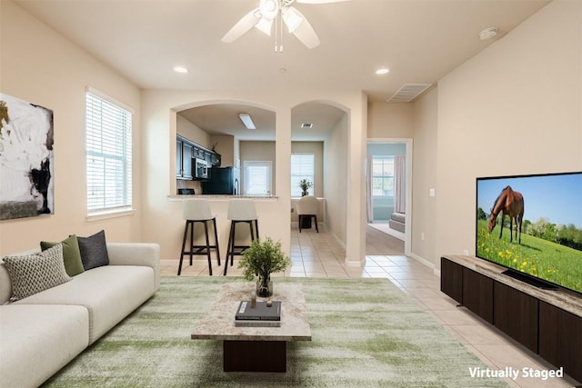 living room with visible vents, a ceiling fan, light tile patterned floors, and a healthy amount of sunlight