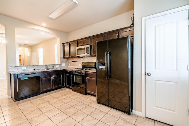2880UNIT3401 Donnell Dr Unit 3401, Round Rock, TX 78664 - kitchen featuring black appliances, arched walkways, decorative backsplash, light tile patterned flooring, and dark brown cabinets