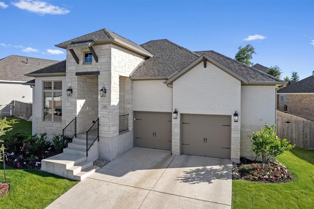 french country home with fence, concrete driveway, roof with shingles, and stone siding