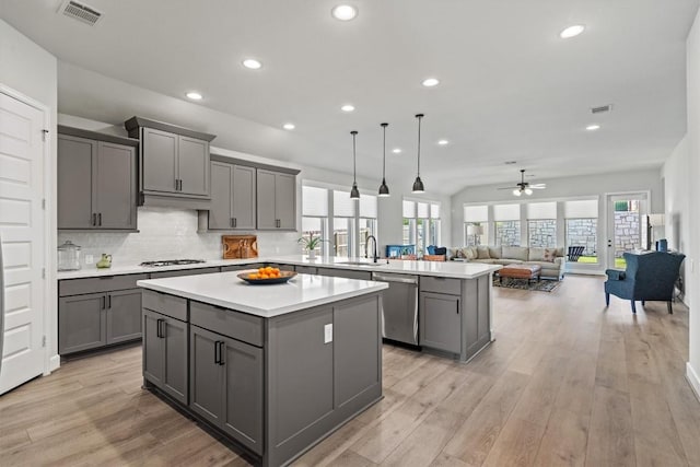 kitchen with gray cabinetry, stainless steel dishwasher, a kitchen island, and visible vents