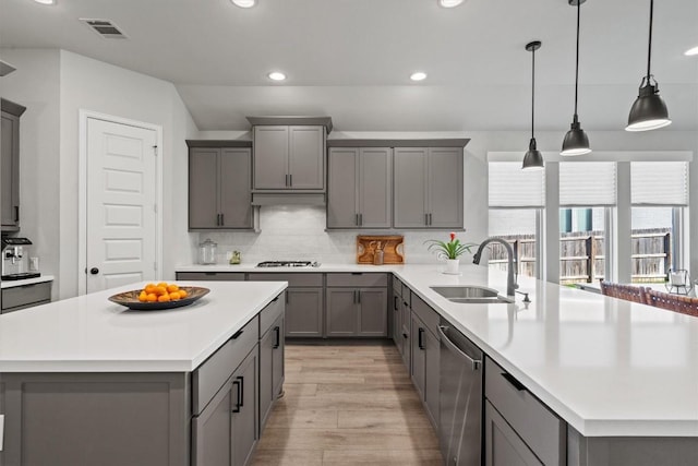kitchen with stainless steel dishwasher, visible vents, a peninsula, light countertops, and gray cabinetry